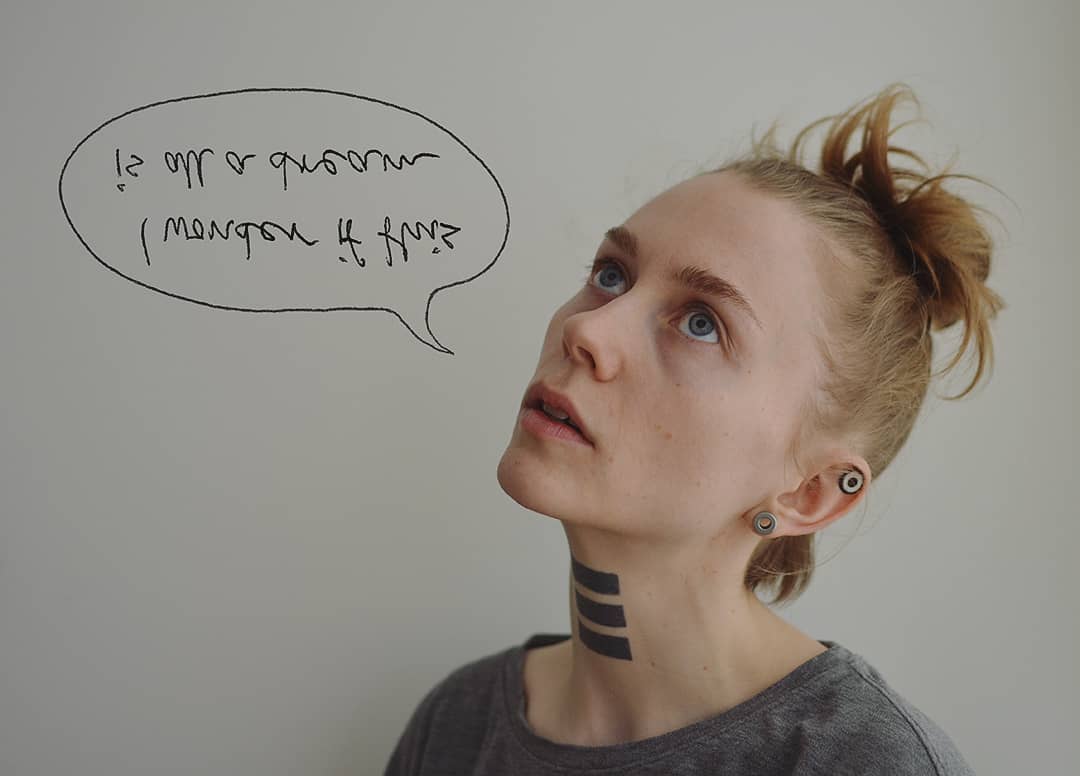 A semiprofile
          photograph of a woman looking upwards, with a speech bubble saying "I
          wonder if this is all a dream" in upside down and mirrored text.